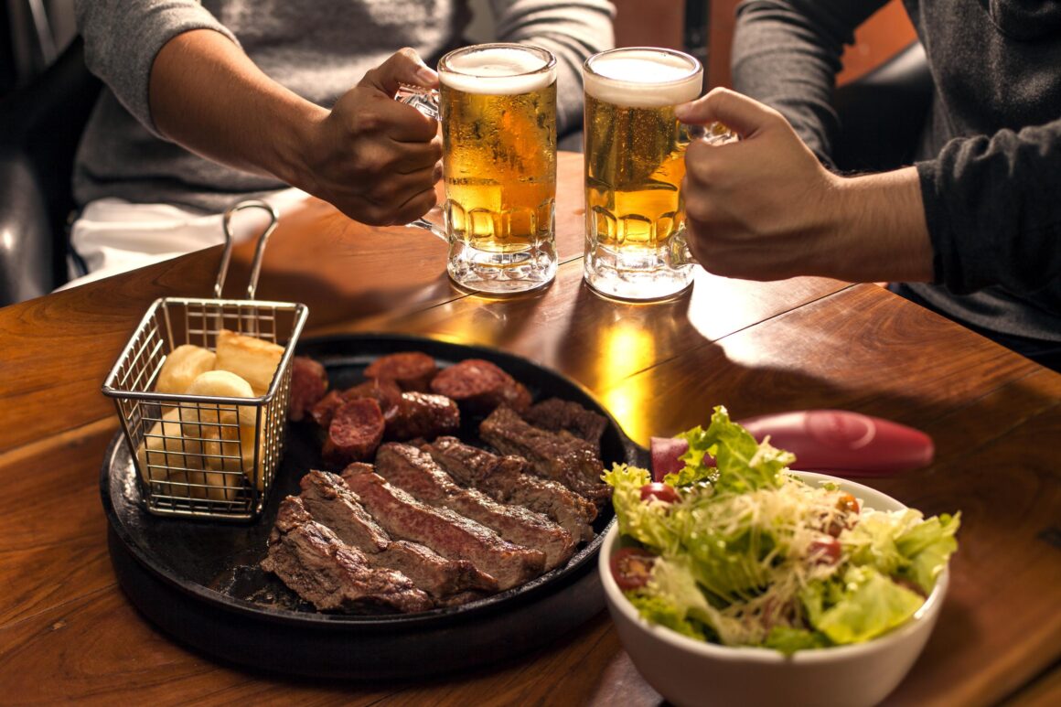 Personas disfrutando cerveza premium con carnes y alimentos en una experiencia de maridaje